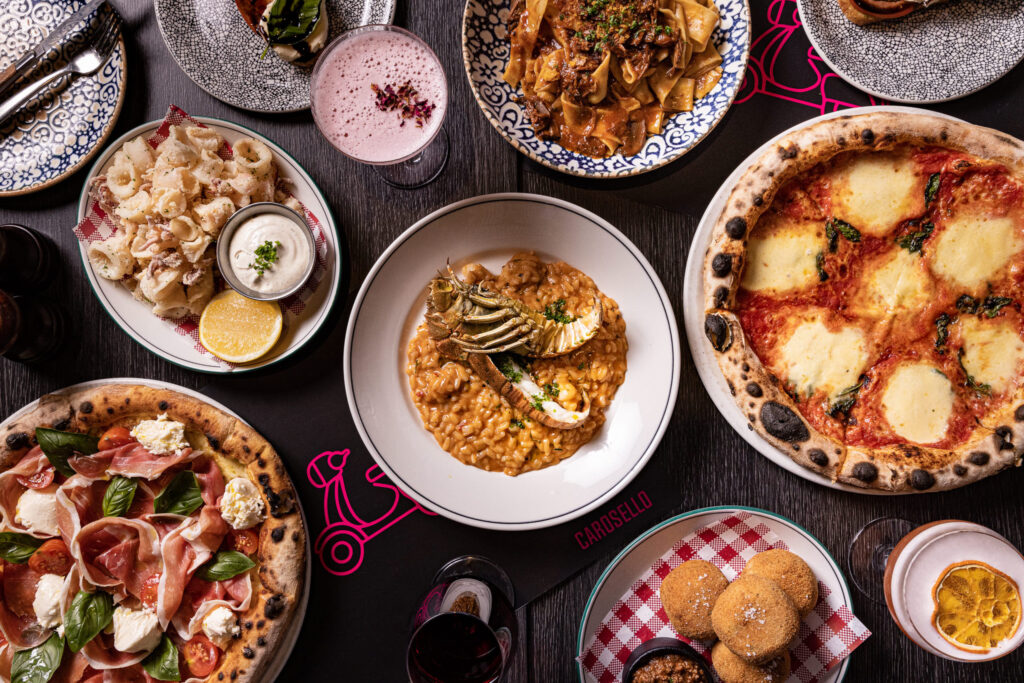 Italian dishes sitting on a table. There is a risotto in the middle, surrounded by pizza and pasta dishes.